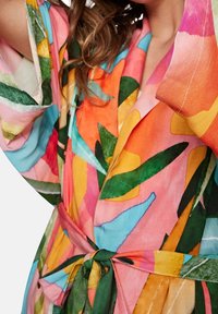 Robe dai colori vivaci caratterizzato da un motivo tropicale con grandi foglie nei toni di verde, rosa, arancione e blu. Realizzato in un tessuto leggero con vita regolabile.