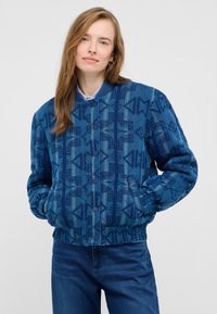 Niebieska pikowana kurtka bomberka z geometrycznymi wzorami, ściągaczami przy mankietach i guzikami. Dwie przednie kieszenie oraz gładkie niebieskie podszycie.
