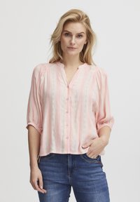 Blusa rosa chiaro con righe verticali di un rosa più scuro. Presenta un colletto a V, chiusura con bottoni e maniche a tre quarti con una vestibilità morbida.