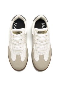 Zapatillas blancas y beige con un upper de ante texturizado y cuero suave, que presentan cordones, perforaciones y un acento de logo dorado.