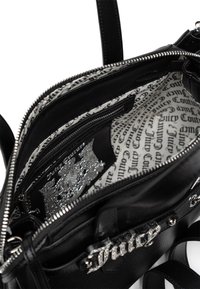 Czarna skórzana torebka na ramię z srebrnym okuciem, wnętrze wyściełane czarno-białym nadrukiem Juicy Couture, posiada zamykane na zamek przegrody i akcenty.