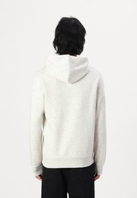 Lys grå hættetrøje lavet af blødt stof, med en snoretrækshætte og ribbede manchetter, med et enkelt design og uden synlige logoer.