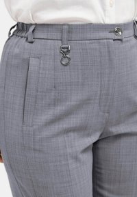 Grijze, op maat gemaakte broeken met een textuurafwerking, voorzien van een strakke tailleband, een zilveren gespaccent en zijzakken.