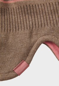 Braun gestrickter Stoff mit gerippter Textur, der ein pinkes Innenfutter und ein pinkes Etikett mit der Aufschrift "maximo" aufweist. Kreisförmiger Ausschnitt für Funktionalität.