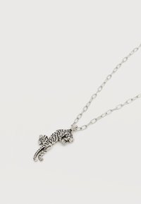 Ασημένιο κολιέ αλυσίδας με ένα λεπτομερές, υφασμένο μενταγιόν σε σχήμα τίγρης, τοποθετημένο σε λευκό φόντο.
