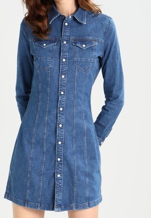 Dopasowana niebieska sukienka z denimu z długimi rękawami, zapięciem na guziki z przodu, kołnierzykiem oraz dwoma kieszeniami na piersi z patkami i guzikami.