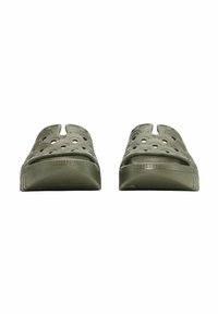 Sandales vertes à enfiler avec découpes circulaires, fabriquées en matériau léger. Elles présentent une semelle plate et un design ouvert au niveau des orteils.