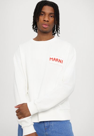 Valkoinen neuletakki pitkillä hihoilla, pyöreällä kaula-aukolla ja punaisella "MARNI"-logopatchilla vasemmassa rinnassa. Pehmeä, tekstuuri kangas.