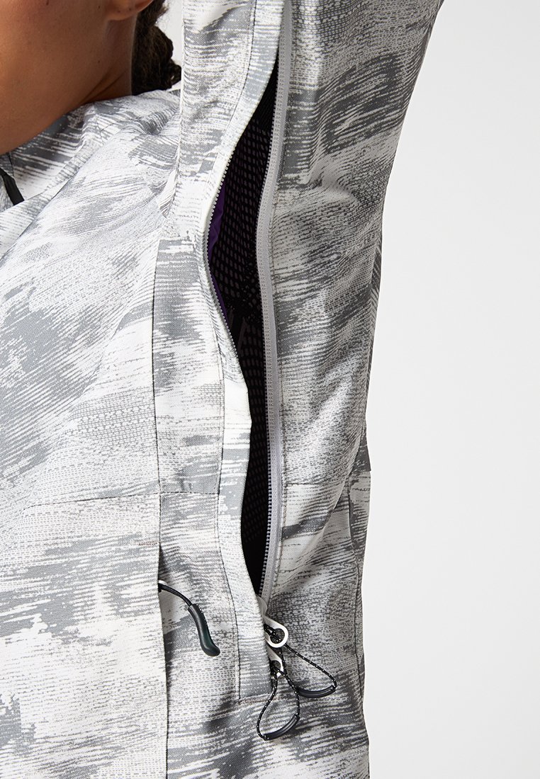 Chaqueta ligera con un patrón abstracto en gris y blanco, que cuenta con un bolsillo con cremallera y una tela texturizada para mayor transpirabilidad.