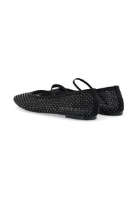 Bailarinas negras con parte superior de malla texturizada, adornadas con pequeños studs decorativos. Presentan una suela plana y correas cruzadas duales.