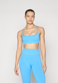 Sutia desportivo azul claro e leggings de cintura alta em tecido suave. O sutia apresenta alças finas; as leggings são ajustadas ao corpo com um design sem costuras.