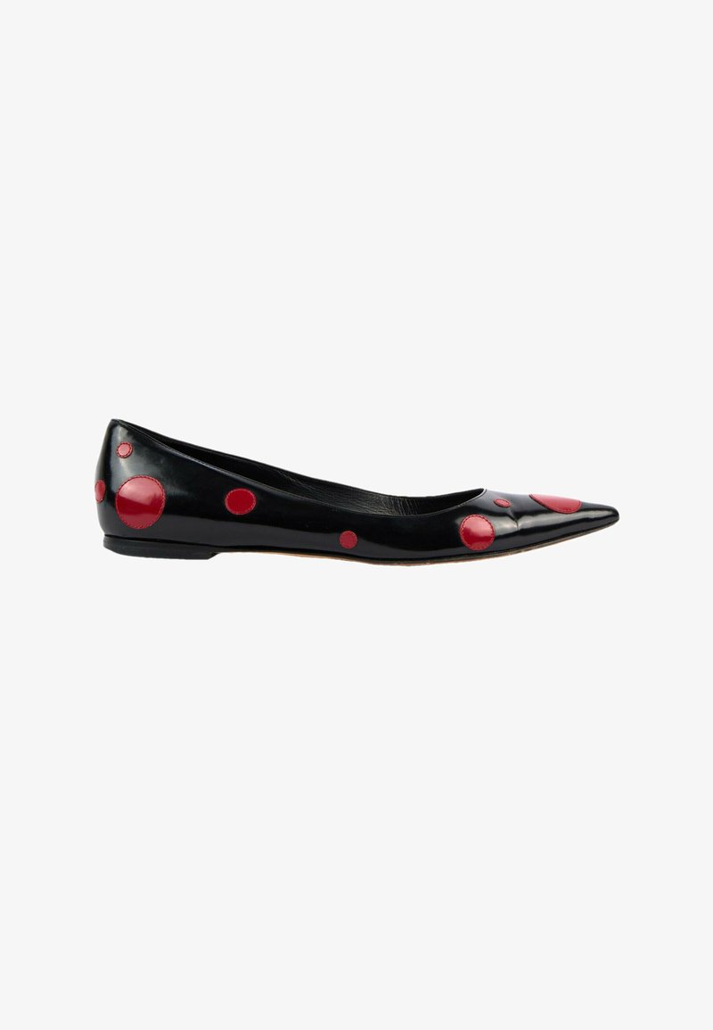 Chaussure plate noire pointue avec des taches circulaires rouges de tailles variées sur la tige et le talon.