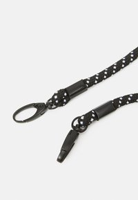 Svart flätad tygsnodd med vita accenter, med två svarta metallklämmor för fäste. Inkluderar en plastkoppling.