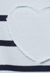 Tessuto a maglia a strisce in blu chiaro e blu navy, con un'applicazione a forma di cuore sfrangiata al centro. Texture liscia con un netto contrasto di colori.