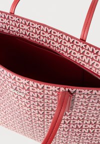 Punane kandekott lõuendist välispinnaga, millel kordub logo muster. Siledad nahast sangad ja luku sulgemine rikkaliku sisustusega.