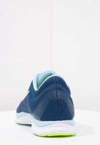 Scarpe sportive blu navy con tomaia in rete e accenti azzurri, dotate di un colletto imbottito e una suola bianca con dettagli verdi sulla parte inferiore.