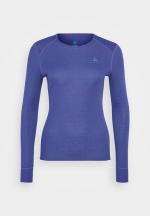 Long-sleeve fitted blue athletic shirt with crew neck and small logo on upper left chest, displayed on a plain white background.