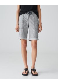 Gray striped shorts with rolled cuffs, featuring side pockets and a drawstring waistband, paired with black flip-flop sandals.