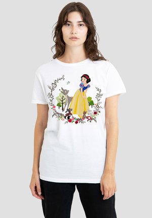 White cotton t-shirt featuring an illustration of a character in a yellow dress surrounded by trees and animals, with floral accents.