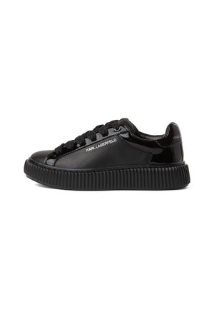 Baskets noires avec une finition laquée brillante, bout rond, semelle épaisse à stries, et lacets noirs. Le nom de la marque est embossé en blanc sur le côté.