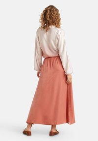 Maxikleid mit einem leichten, rosa Satinoberteil und einem fließenden korallenfarbenen Rock. Verfügt über lange Ärmel, einen elastischen Taillenbund und einen seitlichen Schlitz.