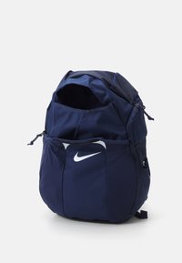 Sac à dos Nike bleu marine avec un tissu texturé, ouverture par le haut et poche avant arborant un logo swoosh blanc. Bretelles réglables sur les côtés.