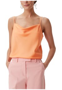 Brzoskwiniowa satynowa koszulka na ramiączkach z cienkimi paskami i luźnym krojem, w połączeniu z jasnoróżowymi eleganckimi spodniami. Gładka faktura o subtelnym połysku.