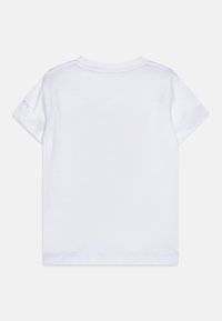 T-shirt en coton blanc à manches courtes, encolure ras du cou, avec un petit logo en bleu clair sur la manche gauche. Texture simple et lisse.