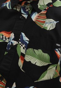 Camicetta a maniche corte in cotone nero con fantasie di foglie colorate e a scacchi, dotata di colletto button-down e taschino sul lato sinistro del petto.