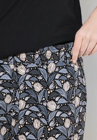 Svarta pyjamasbyxor med ett blommönster i ljusblått och mjukt rosa, med en elastisk midja och en slät tygtextur.