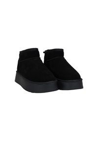 Botines de ante negro con una suela de goma plana y texturizada, y un diseño minimalista. Presentan un upper suave y detalles cosidos a lo largo de los bordes.