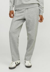 Pantalones de chándal grises hechos de una tela suave, con un corte holgado, cinturilla elástica, bolsillos laterales y sutiles detalles de costura.
