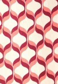 Tessuto con un motivo ondulato in tonalità di rosa e rosso su uno sfondo crema, caratterizzato da una superficie testurizzata e curve morbide.