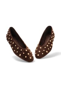 Bailarinas de ante marrón adornadas con acentos de tachuelas doradas. Presentan una punta redonda y una superficie texturizada.