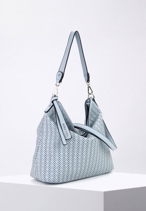 Sac à main en cuir bleu clair avec motif floral perforé, bandoulière unique et petite étiquette attachée, posé sur un socle blanc.