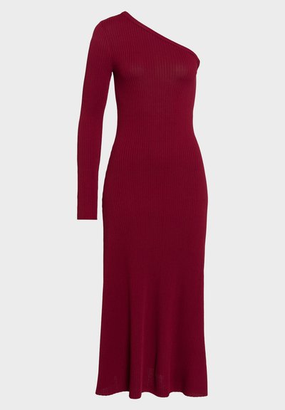 Robe à manches longues côtelées de couleur rouge profond, présentant un décolleté asymétrique et une silhouette ajustée qui se termine par un ourlet légèrement évasé.