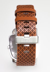 Brun perforeret læderurrem med spænde i sølvstål, der har flere justeringshuller og en rektangulær urskive.