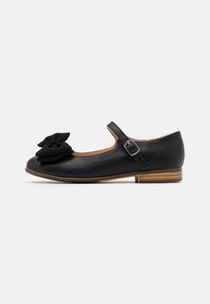 Chaussure Mary Jane en cuir noir avec bride réglable à boucle, petit talon en bois et grande décoration florale en tissu sur l'avant.
