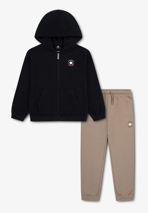 Czarna bluza z kapturem i zamkiem oraz beżowe spodnie z elastycznym paskiem, obie z małymi logo Converse All Star.