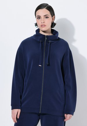 Sweat à capuche zippé bleu marine en tissu doux, doté d'un col montant, de liens à cordon, et de poches latérales, avec une coupe décontractée et des manches longues.
