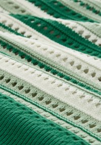 Manta de ganchillo con franjas alternas de verde y blanco, con patrones texturizados y detalles de calado en toda su superficie.