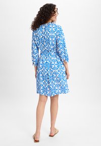 Blauw en wit gestreepte jurk met driekwart mouwen, tailleband en knoopdetail op de rug, gemaakt van lichtgewicht stof.