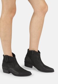 Bottines noires avec une combinaison de cuir lisse et de daim, bout pointu, petit talon empilable, et une fermeture éclair sur le côté pour un enfilage facile.