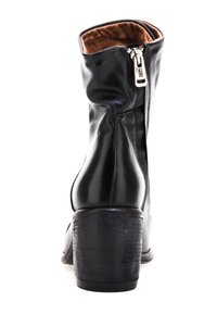 Botín negro de cuero con un acabado suave, cremallera lateral y tacón cuadrado. El forro interior es marrón. El botín se ajusta alrededor del tobillo.