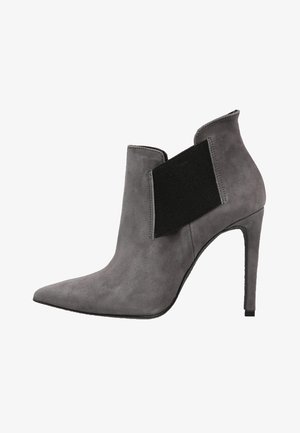 Bottine en suède gris à talon haut, bout pointu et panneau latéral élastique noir pour un enfilage facile.