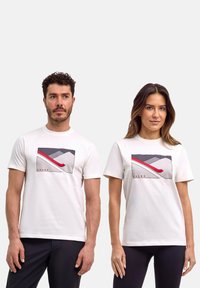 Weiße Baumwoll-T-Shirts mit einem Berggrafik, die graue, rote und schwarze Akzente aufweist. Runder Halsausschnitt, kurze Ärmel, lockere Passform.