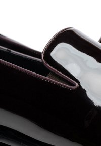 Glänzender bordeauxroter Lacklederschuh zum Hineinschlüpfen mit abgerundetem Zehenbereich, elastischen Seiteneinsätzen und kontrastierenden Nähten entlang der Kanten.