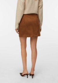 Bruine suède mini-jurk met een gladde textuur, gekenmerkt door een strakke silhouet en schone lijnen. Gekocht in combinatie met open teen muiltjes met hak.