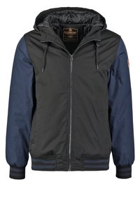 Veste à capuche noire et marine avec fermeture éclair avant, cordons de serrage, poignets et ourlet côtelés, et doublure intérieure matelassée.