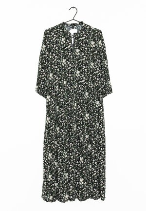 Schwarzes Kleid mit weißem Blumenmuster, 3/4 Ärmel, Ausschnitt am Hals, taillierter Bund, knöchellang, fließende Textur, gewellter Saum. Hängt an einem Haken.